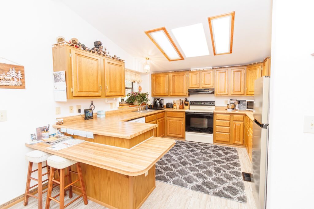 Bright, inviting kitchen with wooden cabinets, a cozy breakfast bar, and modern appliances. Skylights enhance natural light, perfect for cooking.