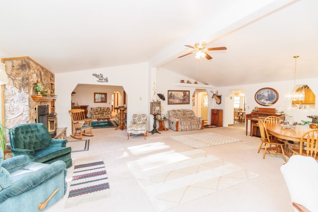 Spacious, rustic living room featuring a stone fireplace, comfortable seating, and dining area, highlighting a cozy, welcoming ambiance.