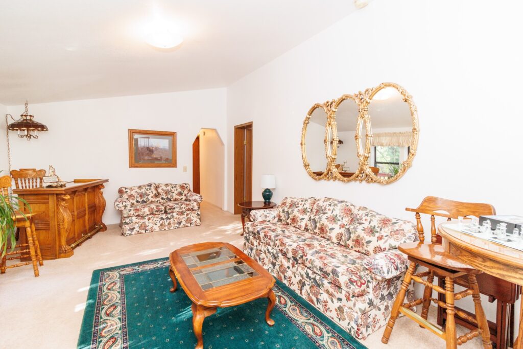 Bright living room featuring floral-patterned couches, a wooden coffee table, and a bar area, creating an inviting space for relaxation and gatherings.