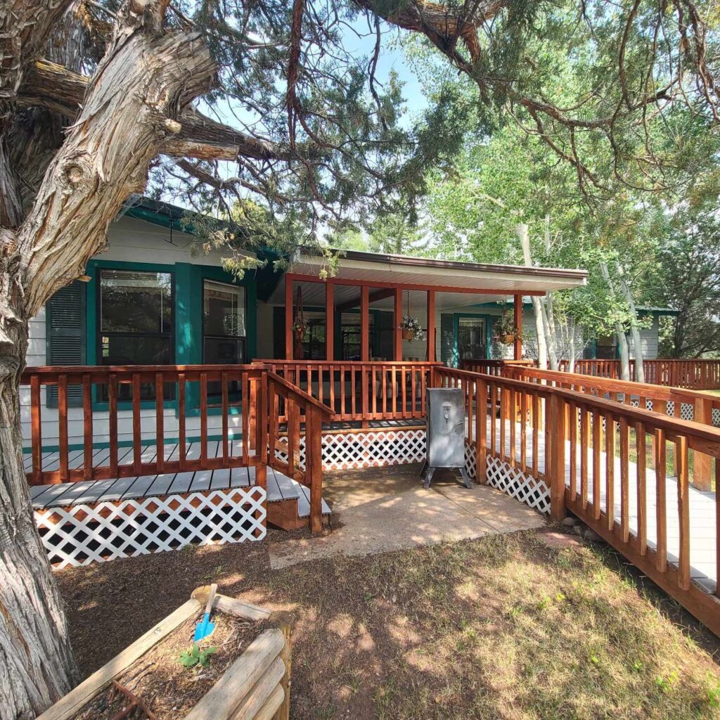Cozy home exterior featuring a wooden deck and ramp, surrounded by trees. Perfect for showcasing outdoor living spaces.
