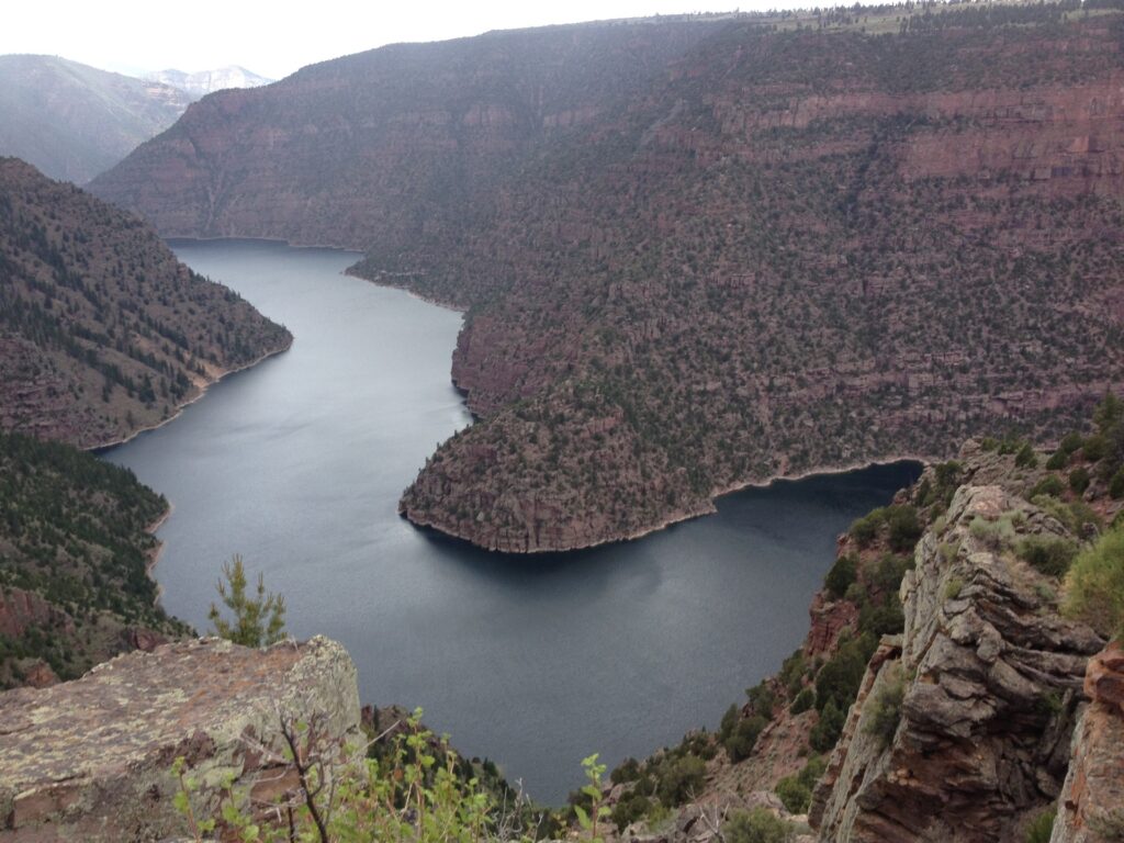 Winding river surrounded by steep, rocky cliffs and lush greenery, showcasing a serene landscape ideal for nature exploration.